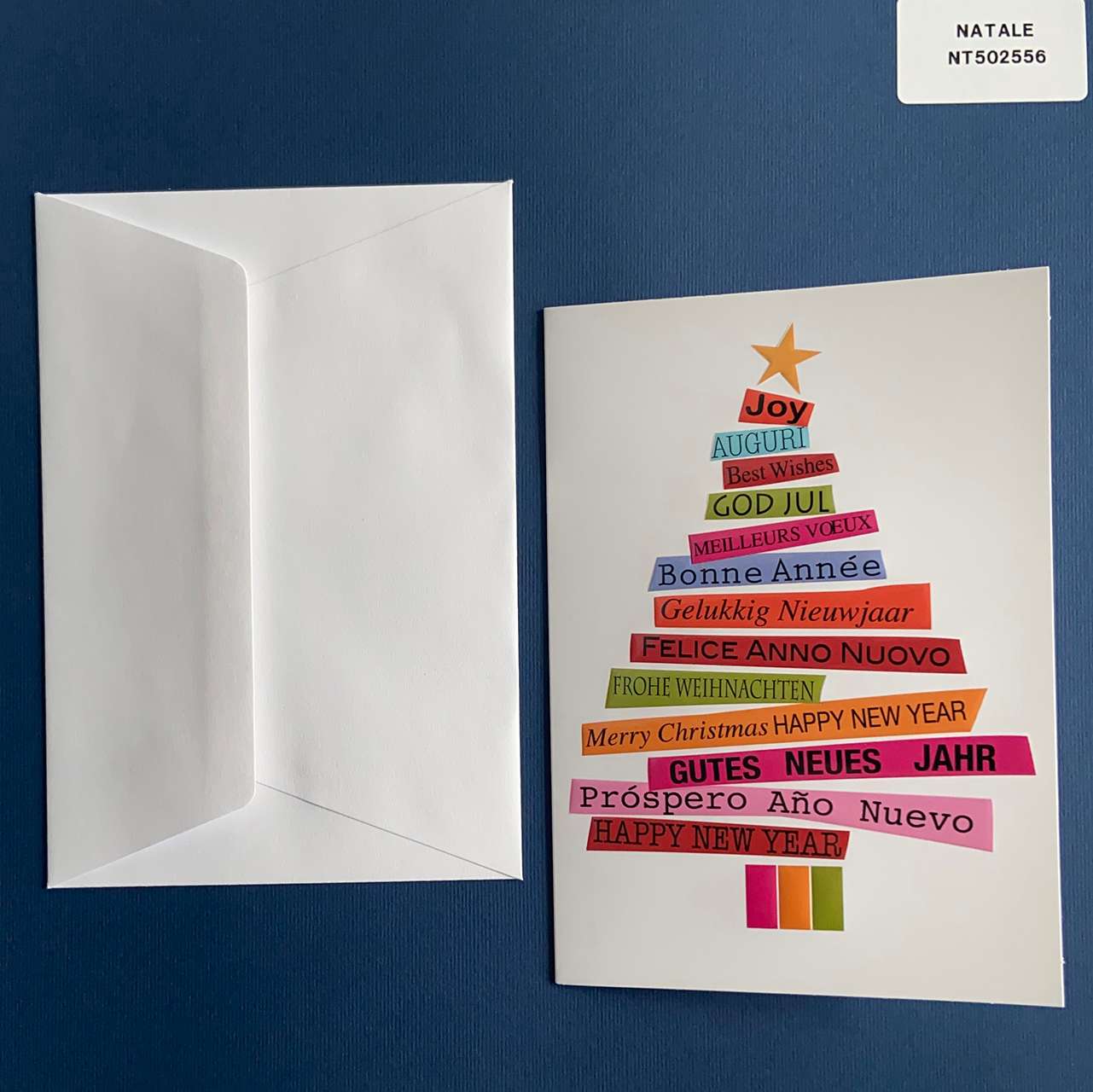 biglietto di Natale a libretto verticale personalizzabile all'interno. In copertina un albero di Natale costituito da tante fascette colorate e scritte natalizie in più lingue